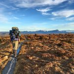 Solo hiker with backpack on a scenic trail at Cradle Mountain, Tasmania.
